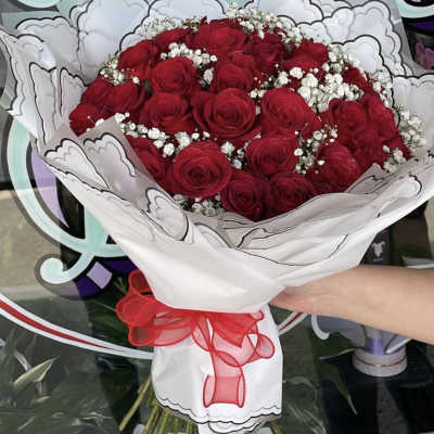 Bouquet of red roses with white baby's breath in white wrapping and a red ribbon