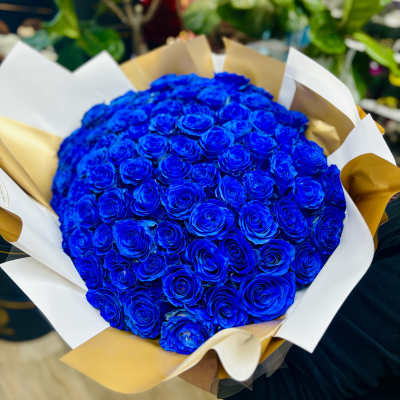 Large bouquet of vivid blue roses wrapped in white and gold paper