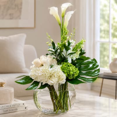 White and green floral arrangement in a round glass vase