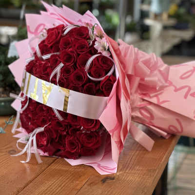 Bouquet of red roses wrapped in pink paper with ribbon