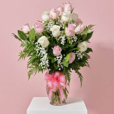 Pink and white roses in a glass vase with a pink ribbon