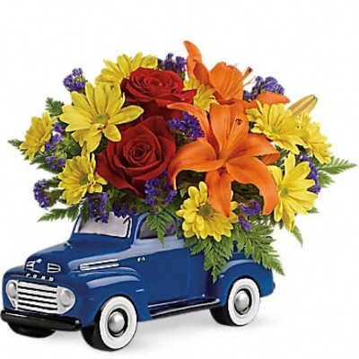 Bouquet of red roses, orange lilies, and yellow daisies in a blue toy truck