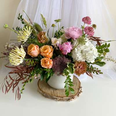 Mixed floral arrangement in a white vase with pink, peach, and white blooms