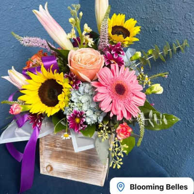 Mixed bouquet with sunflowers, a pink gerbera, and a peach rose in a wooden box