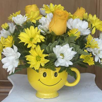 Yellow and white flowers in a smiley-face mug vase