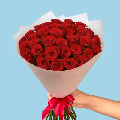 Bouquet of red roses wrapped in white paper with a red ribbon
