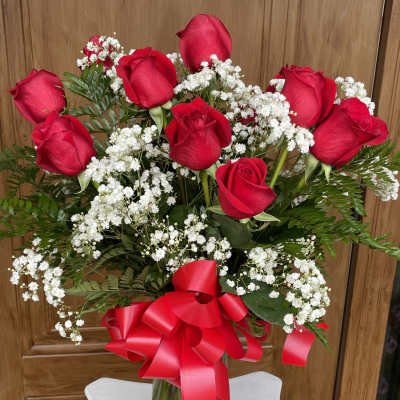 Bouquet of red roses with white baby's breath in a glass vase and red ribbon