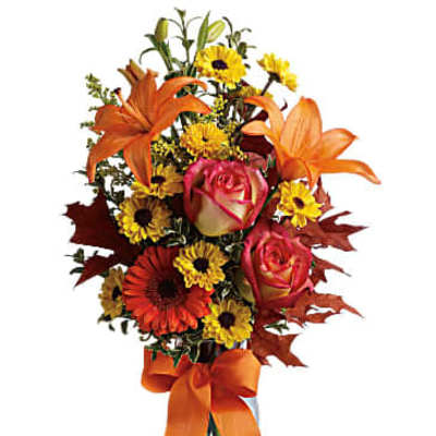 Orange lilies and roses with yellow daisies in a glass vase