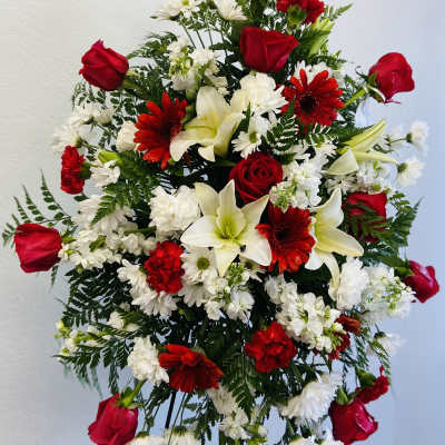Standing floral spray with red roses, white lilies, and red and white daisies