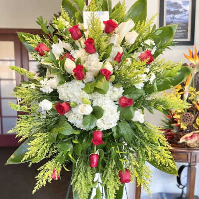 Tall standing spray of red and white roses with white hydrangeas on a green easel