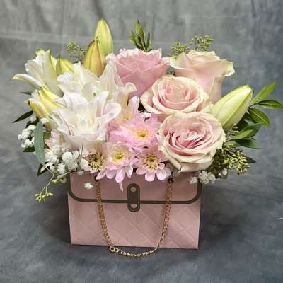 Pink and white flower arrangement in a pink handbag-style box