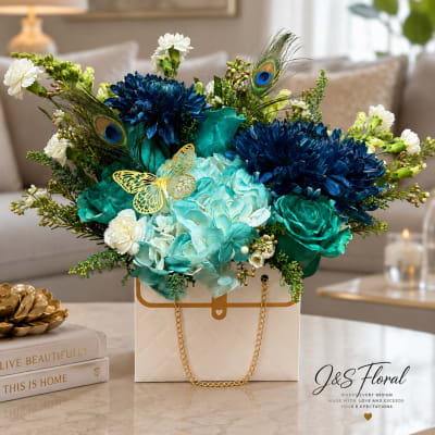Blue and teal floral arrangement in a white gift box with gold chain handles