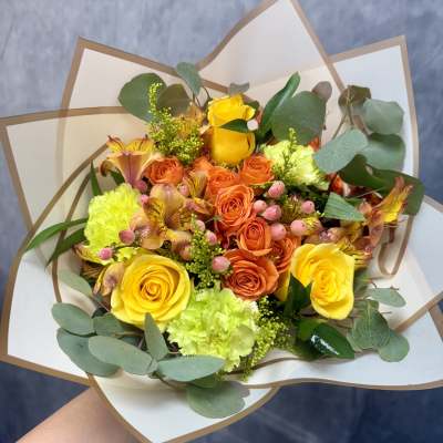 Bouquet of yellow and orange roses with green and pink accents
