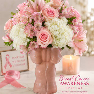 Pink and white floral arrangement in a pink vase with a candle and awareness ribbon