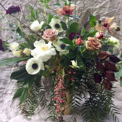 Mixed floral arrangement with roses, white anemones, and dark foliage in a vase