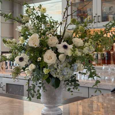 Large white floral arrangement in a gray pedestal vase