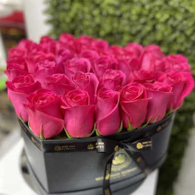 Heart-shaped black box filled with tightly packed hot pink roses
