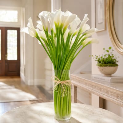 White calla lilies in a clear glass vase tied with raffia