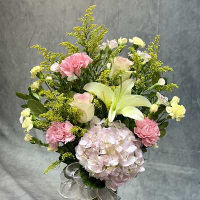 Bouquet of pink and white flowers in a glass vase with a ribbon