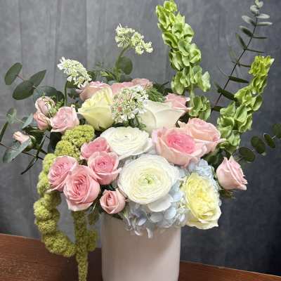 Pink and white roses with ranunculus in a white vase