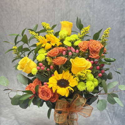 Bouquet of yellow sunflowers and orange roses in a glass vase