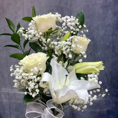White roses and lilies arranged with baby's breath and a sheer ribbon.