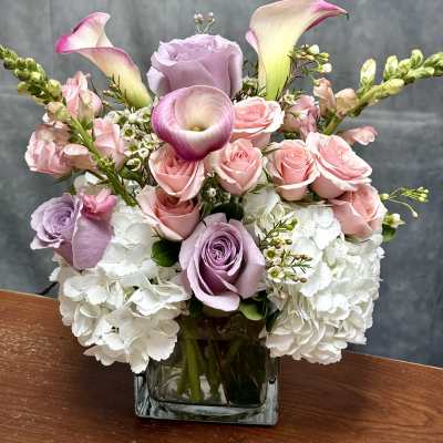 Pink roses and white hydrangeas in a square glass vase with calla lilies