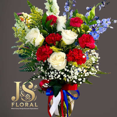 Bouquet of red and white roses with blue flowers in a glass vase