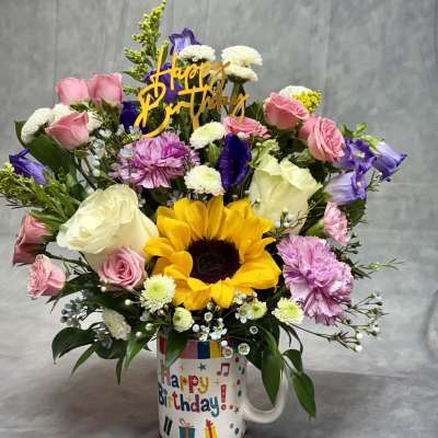 Birthday bouquet in a mug with sunflowers, roses, and mixed blooms