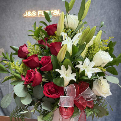 Bouquet of red and white roses with lilies in a white vase