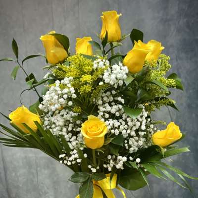 Yellow roses and white baby's breath in a glass vase with a yellow ribbon