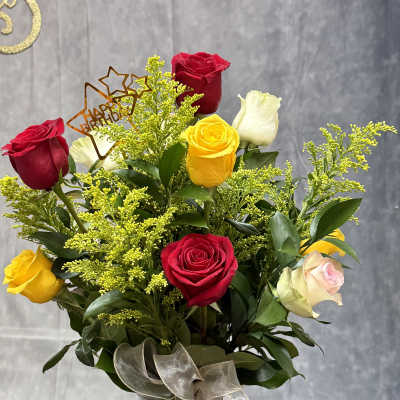 Bouquet of red, yellow, white, and pink roses in a glass vase
