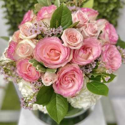 Round arrangement of pink roses with white blooms in a clear glass vase