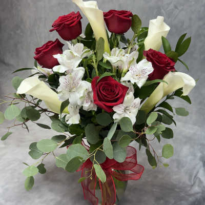 Bouquet of red roses, white calla lilies, and white alstroemeria in a glass vase