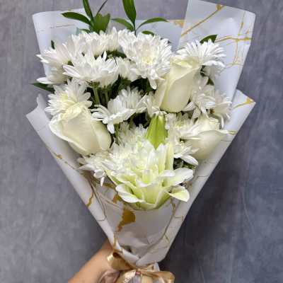 White bouquet with daisies, roses, and a lily wrapped in patterned paper