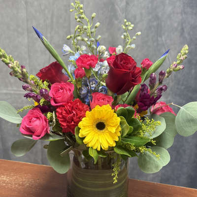 Mixed bouquet of roses, gerbera daisies, and snapdragons in a glass vase
