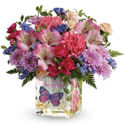 Mixed pink, purple, and blue flowers in a decorated glass vase