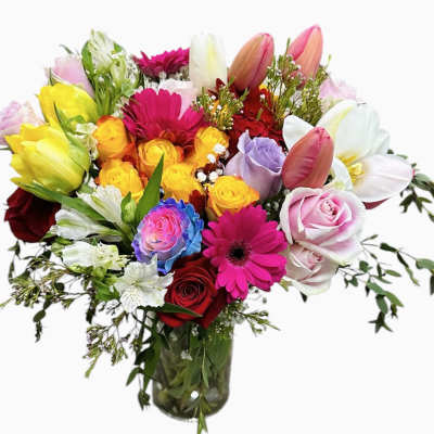 Mixed-color bouquet of roses, tulips, gerbera daisies, and lilies in a clear glass vase