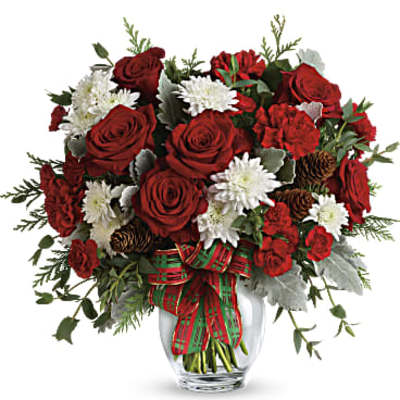 Red roses and white daisies in a clear glass vase with a plaid ribbon
