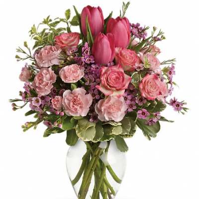 Pink tulips and roses arranged in a clear glass vase