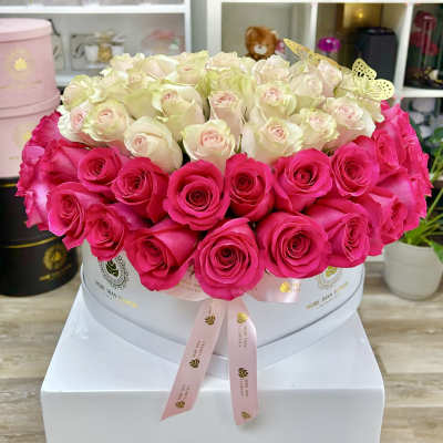 Round hatbox of pale ivory and bright pink roses with a ribbon and gold butterfly accents