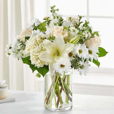 White roses, lilies, and daisies arranged in a clear glass vase