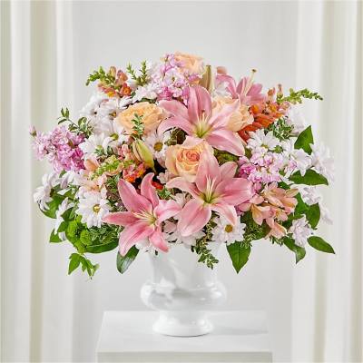 Pink lilies and peach roses in a white pedestal vase