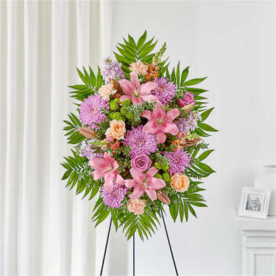Standing floral spray with pink lilies, roses, and purple mums on an easel