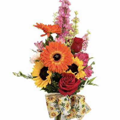 Mixed bouquet with sunflowers, gerbera daisies, roses, and pink blooms in a glass vase