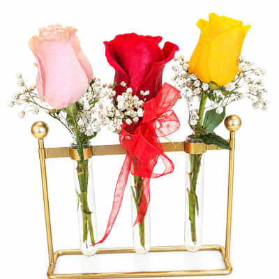 Three roses in glass tubes on a gold stand, with a red ribbon on the center stem
