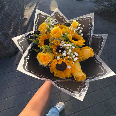 Handheld bouquet of yellow roses and sunflowers with white filler flowers