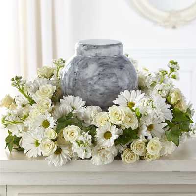 White daisies and roses arranged around a gray urn-shaped vase