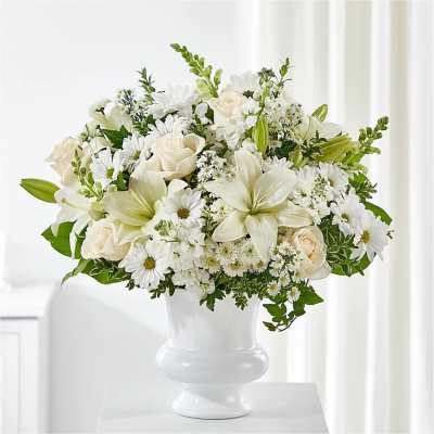White floral arrangement in a white vase with roses and lilies