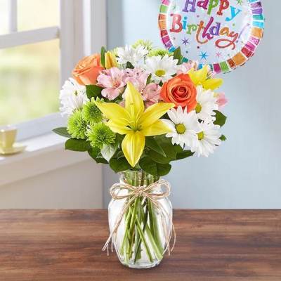 Mixed bouquet in a glass jar with a happy birthday balloon
